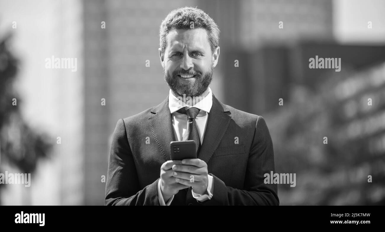 confident man in elegant suit checking email on phone outside ...