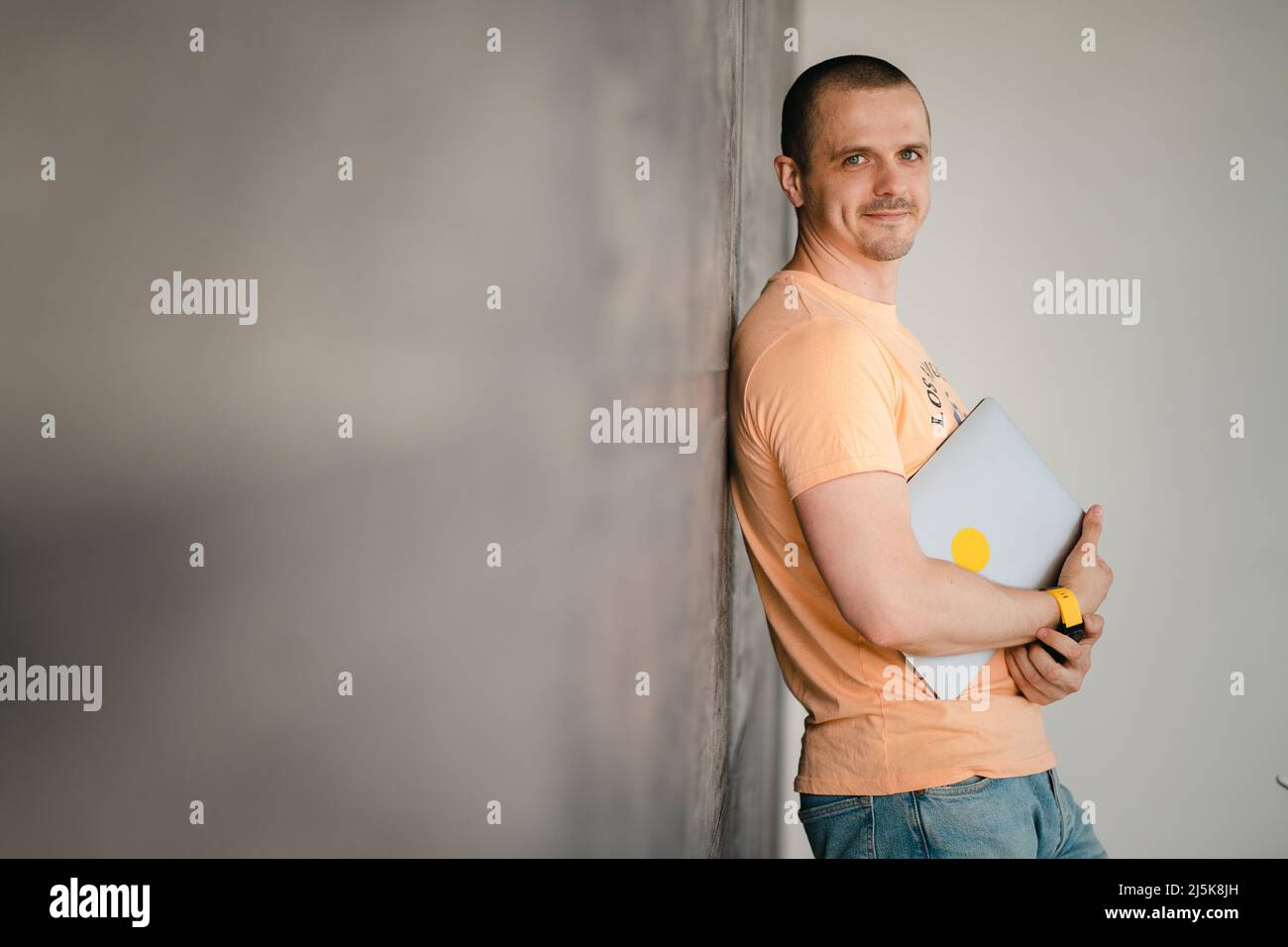 Adult man in yellow t-shirt with laptop Stock Photo