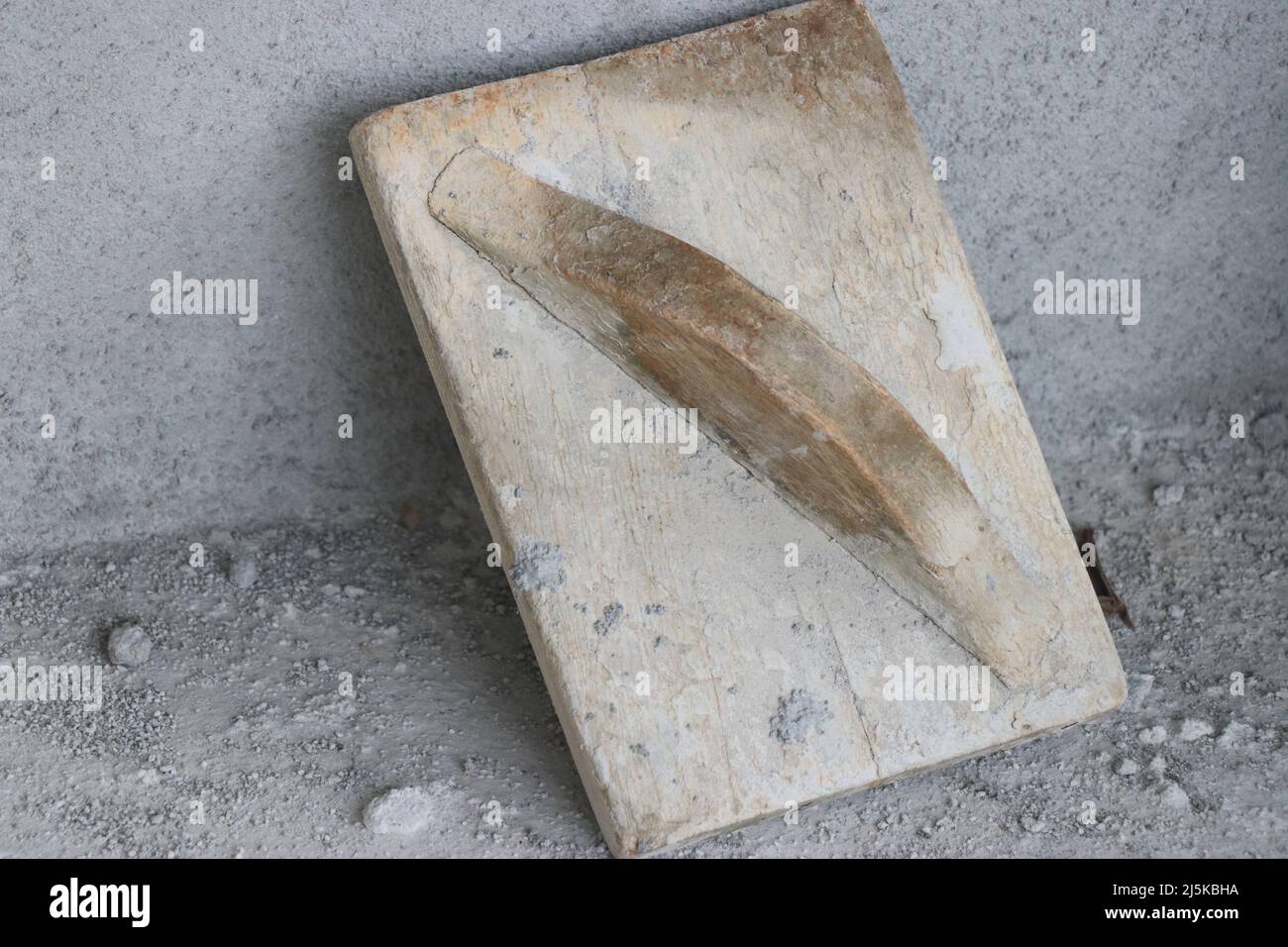 Wooden trowel used for planing concrete surface after plastering. The old way of construction using wooden tools Stock Photo