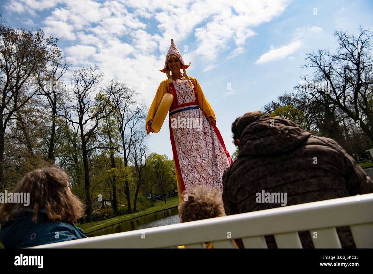 Oranienburg, Germany. 24th Apr, 2022. 'Frau Antje' on stilts greets visitors in the garden of Oranienburg Palace (Brandenburg) during the 'Day in Orange.' The day commemorates the city's namesake, Electress Louise Henriette of Orange. Credit: Paul Zinken/dpa/Alamy Live News Stock Photo