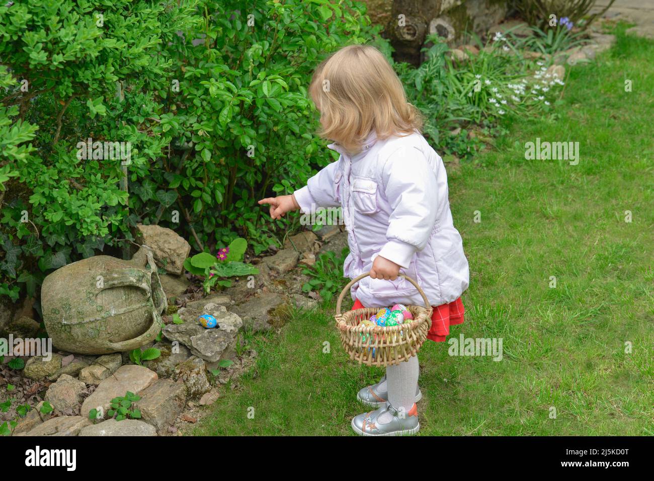 Little girl hunting for easter egg in a spring garden on Easter day