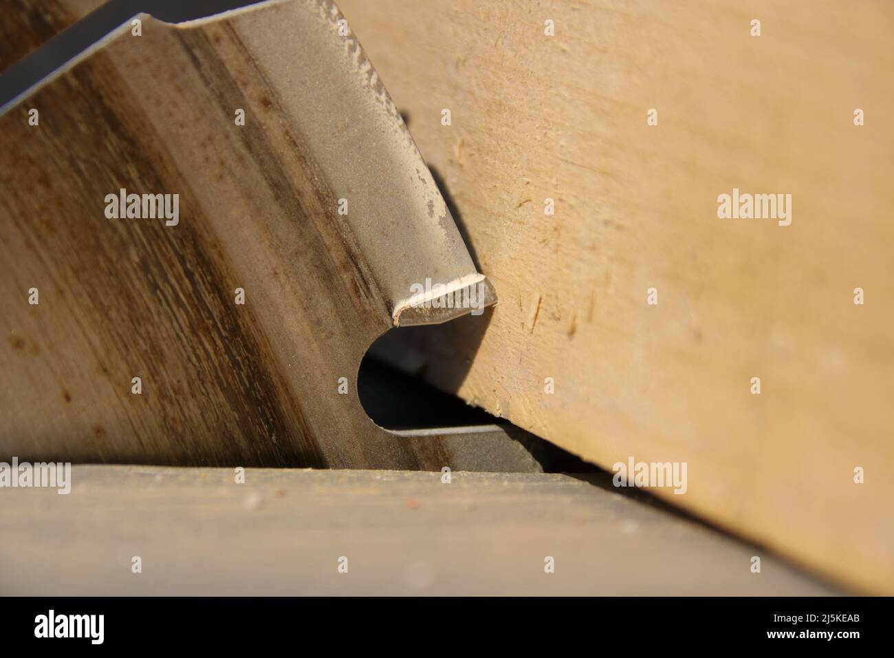 A piece of lumber rests against the saw blade of a circular saw Stock Photo