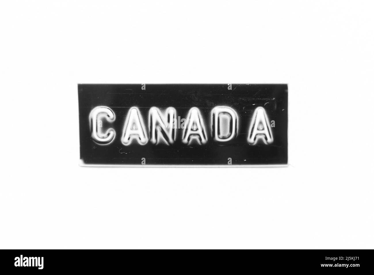 Black color banner that have embossed letter with word canada on white paper background Stock