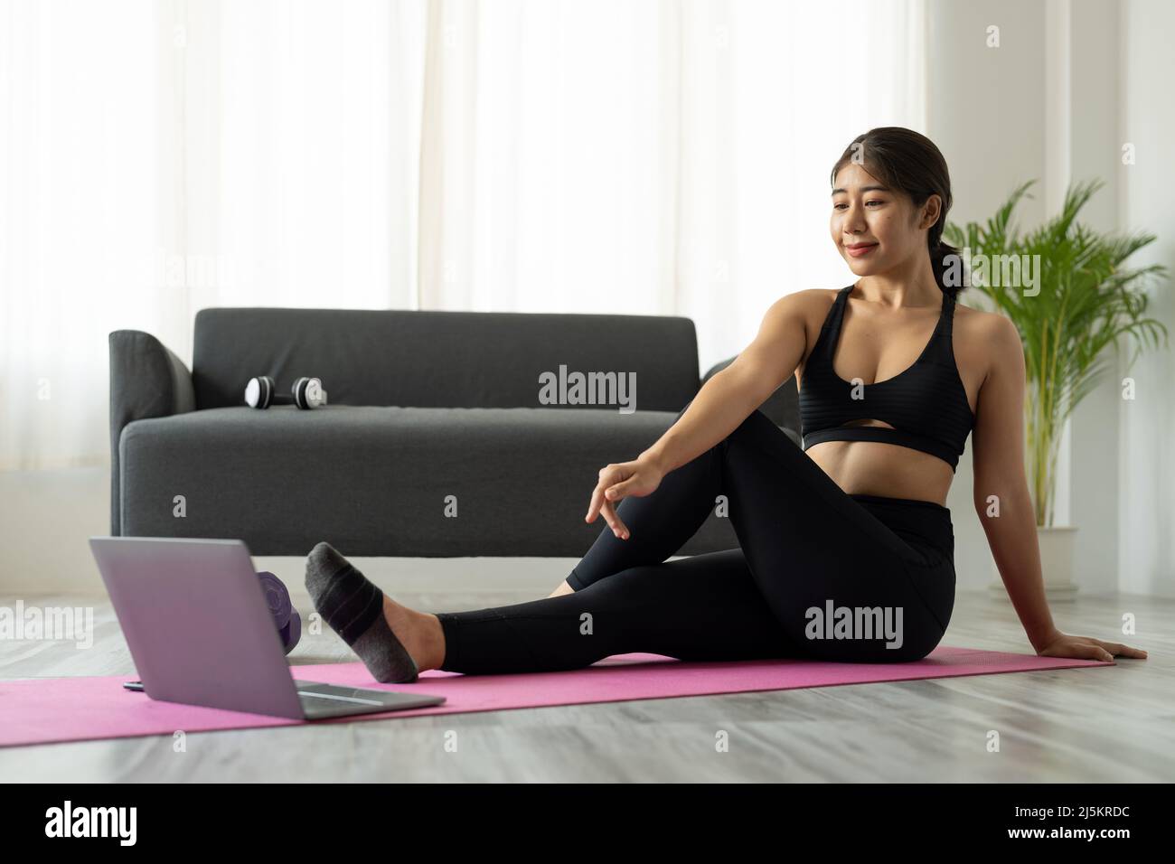 Fit sporty young asian woman online workout exercise at home. Active healthy girl enjoy sport pilates yoga fitness training on laptop computer Stock Photo
