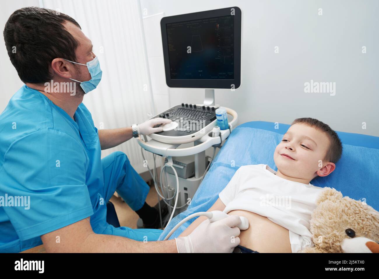 Caring doctor examining the small boy with an ultrasound Stock Photo