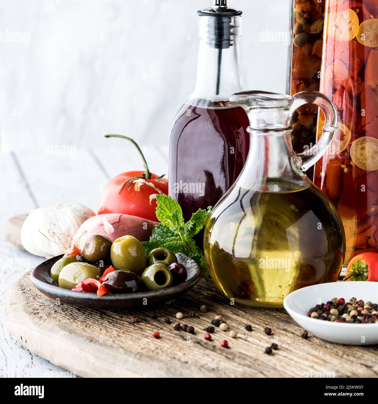 Arrangement of oil and red wine vinegar on a rustic board Stock Photo