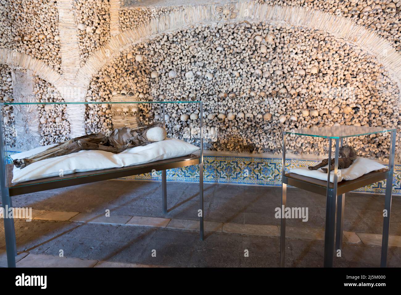 Two desiccated corpses, one of which is a child, in glass display cases inside the Capela dos Ossos ( Chapel of bones) in Evora, Porugal. Stock Photo