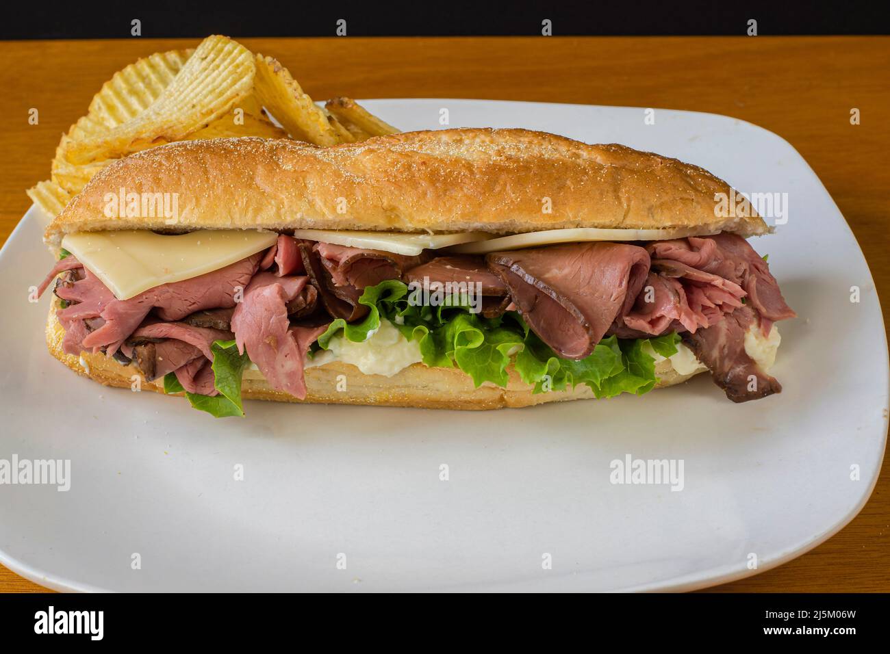 Roast Beef Sub Top With Swiss Cheese And Served With Potato Chips Stock