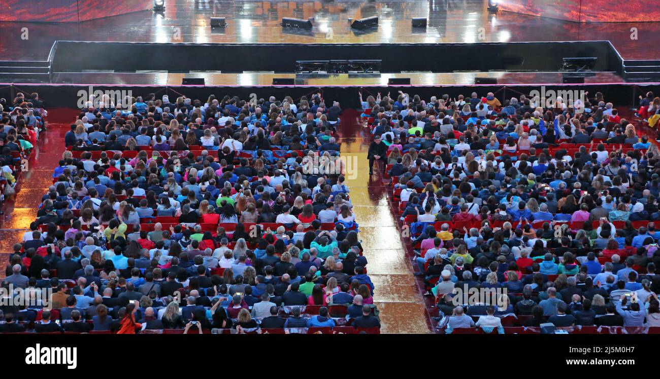 Many people attending the live concert sitting on the seats and the