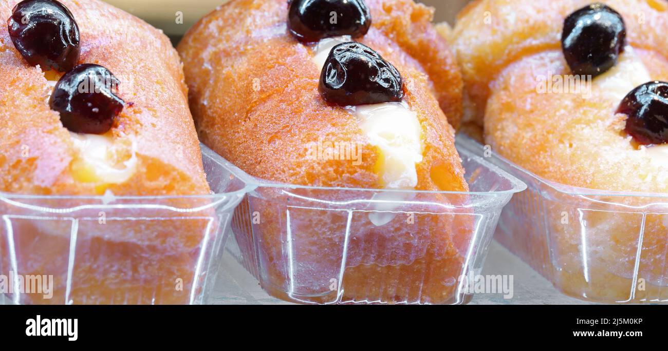 three large rum liqueur babas with cherries on a typical traditional