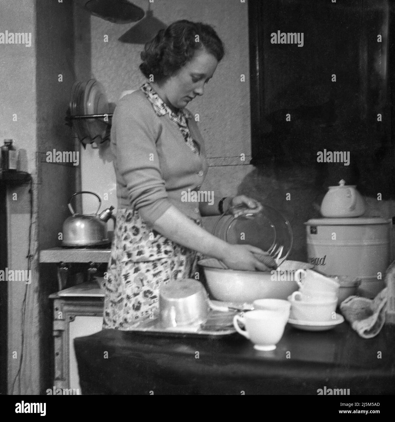 1950s, historical, a woman in a kitchen of the era washing a pryex glass bowl, Stockport, Manchester, England, UK. Stock Photo