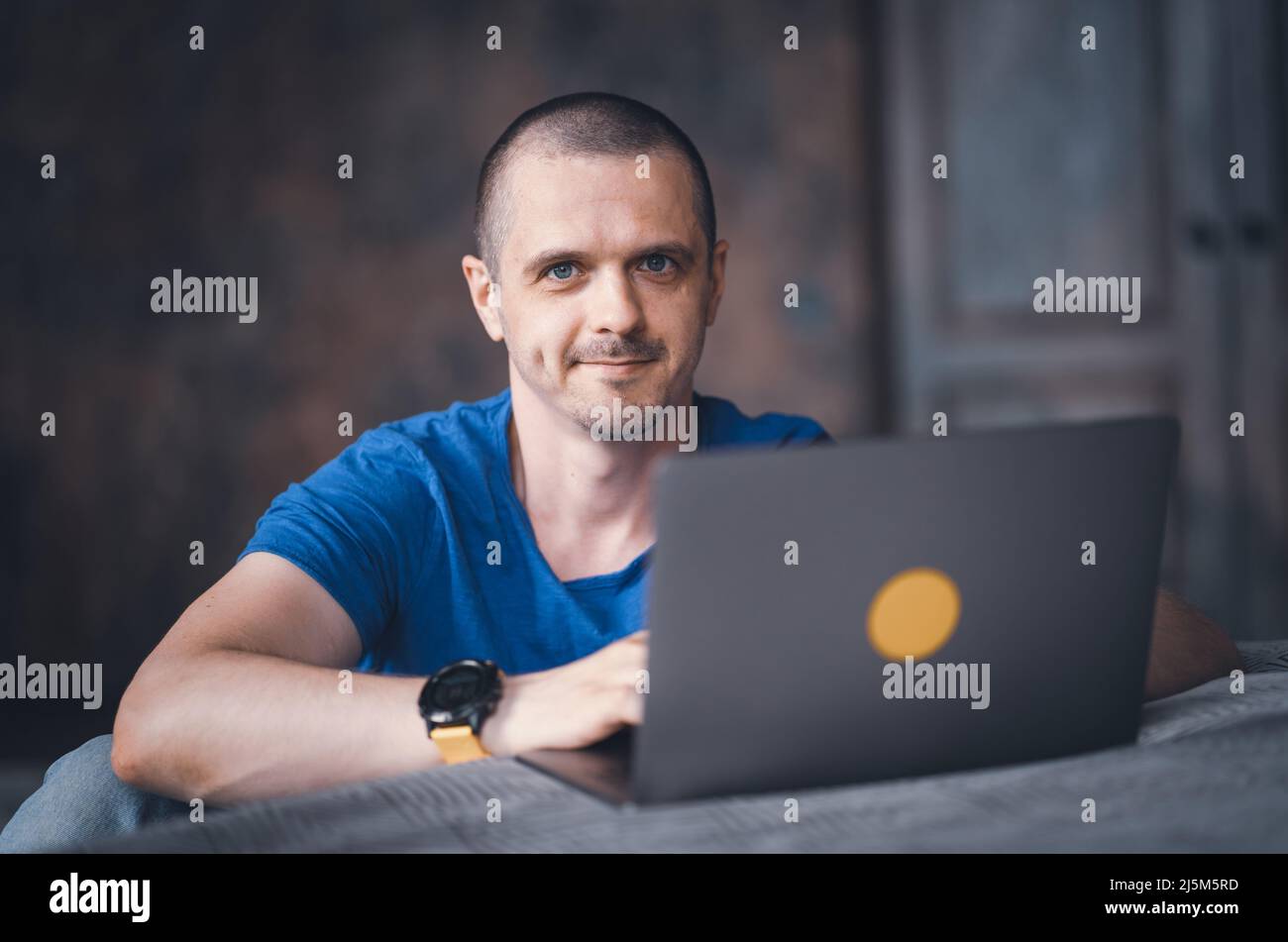 Adult man in blue t-shirt working on laptop Stock Photo