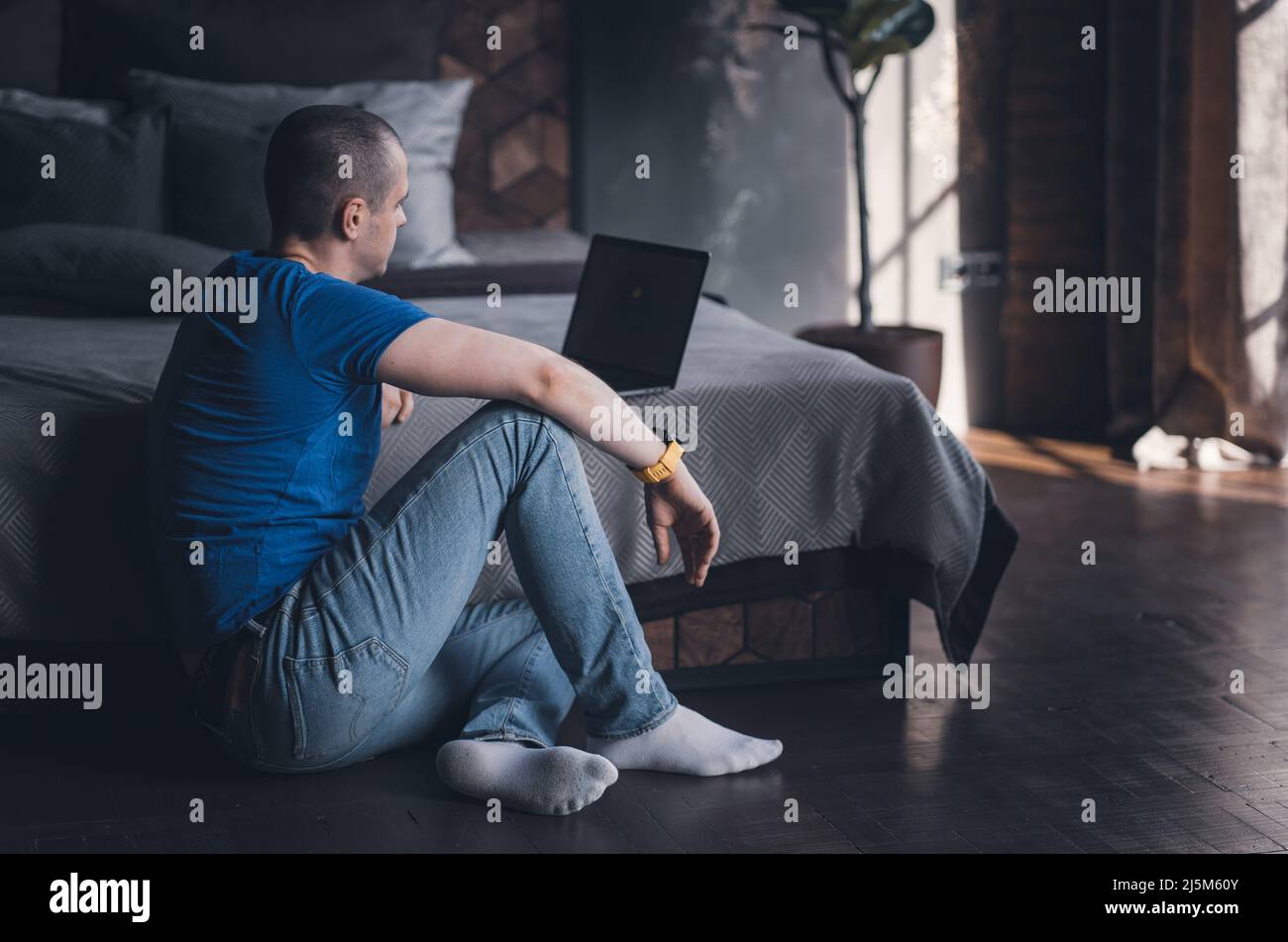Adult man in blue t-shirt working on laptop Stock Photo