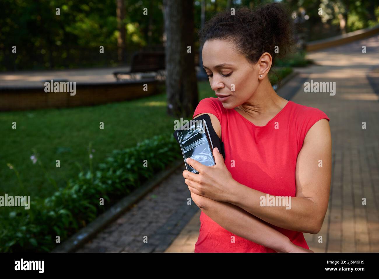 Attractive stunning fit woman in tight red tshirt, athlete adjusting
