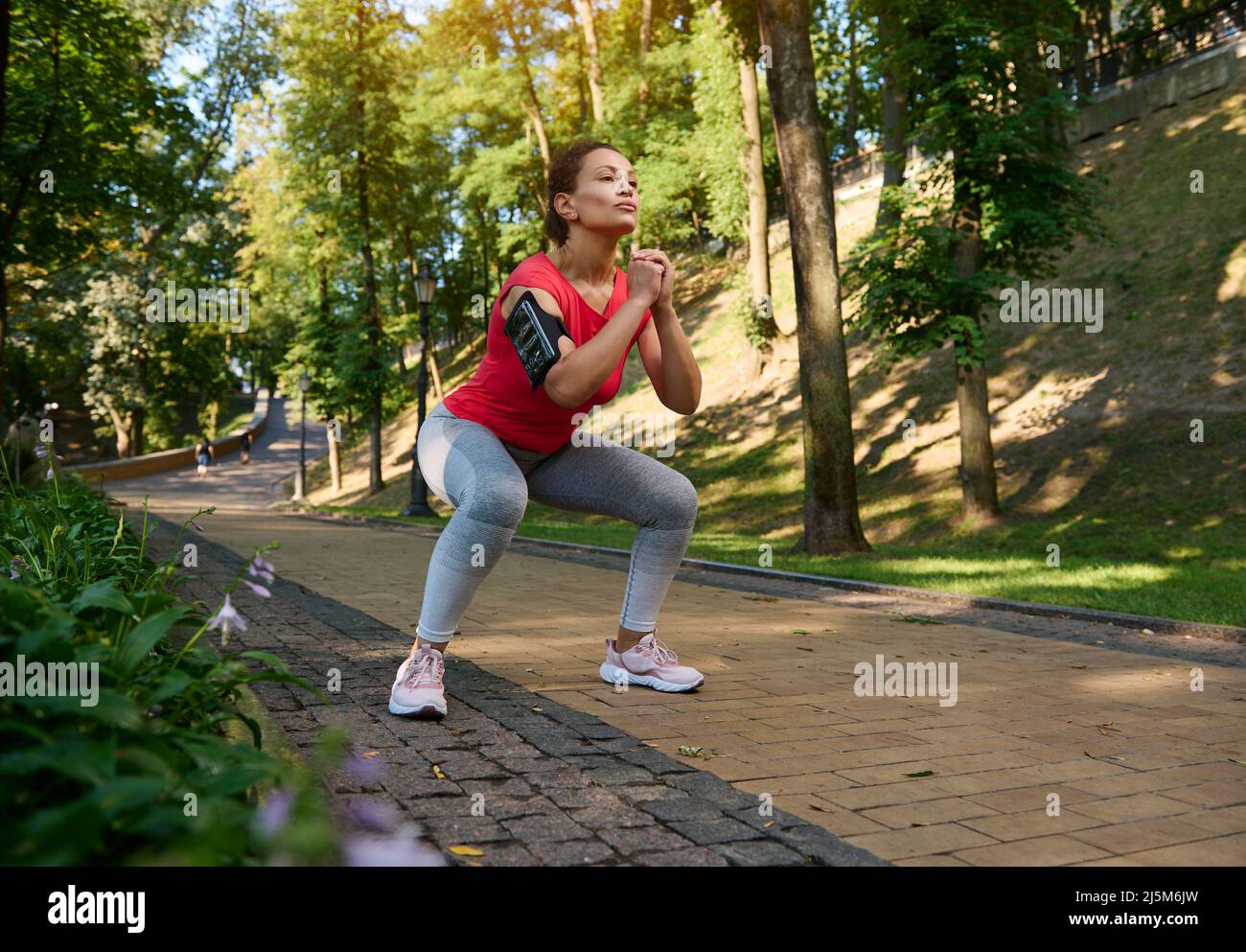 Beautiful confident middle-aged fit woman performing deep squats in the ...