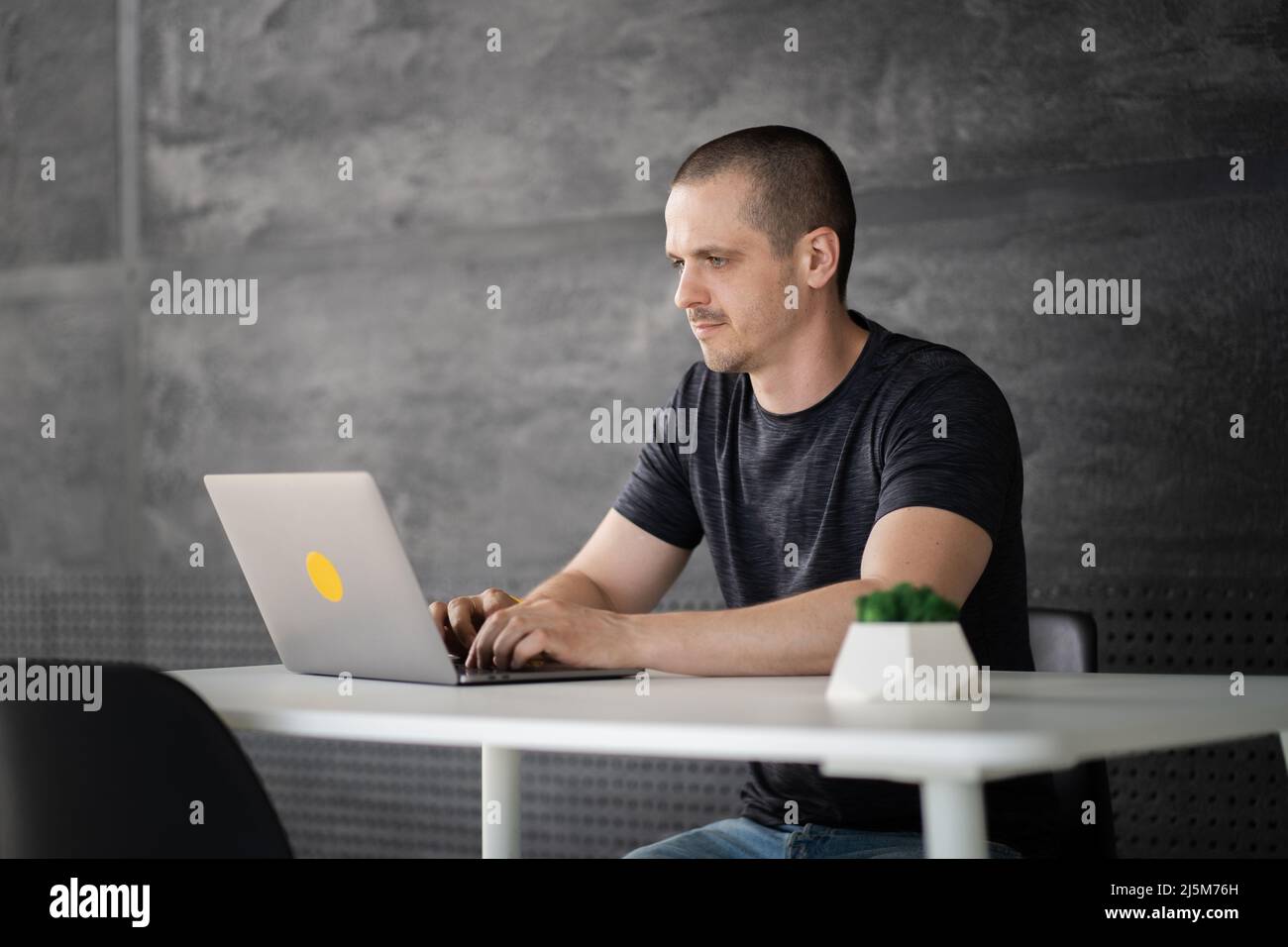 Happy man working on laptop in library or coworking office space Stock Photo