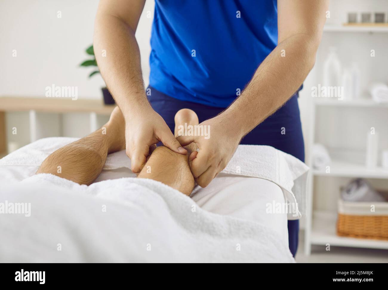 Professional physiotherapist or masseur therapist massages calf muscle of male patient. Stock Photo