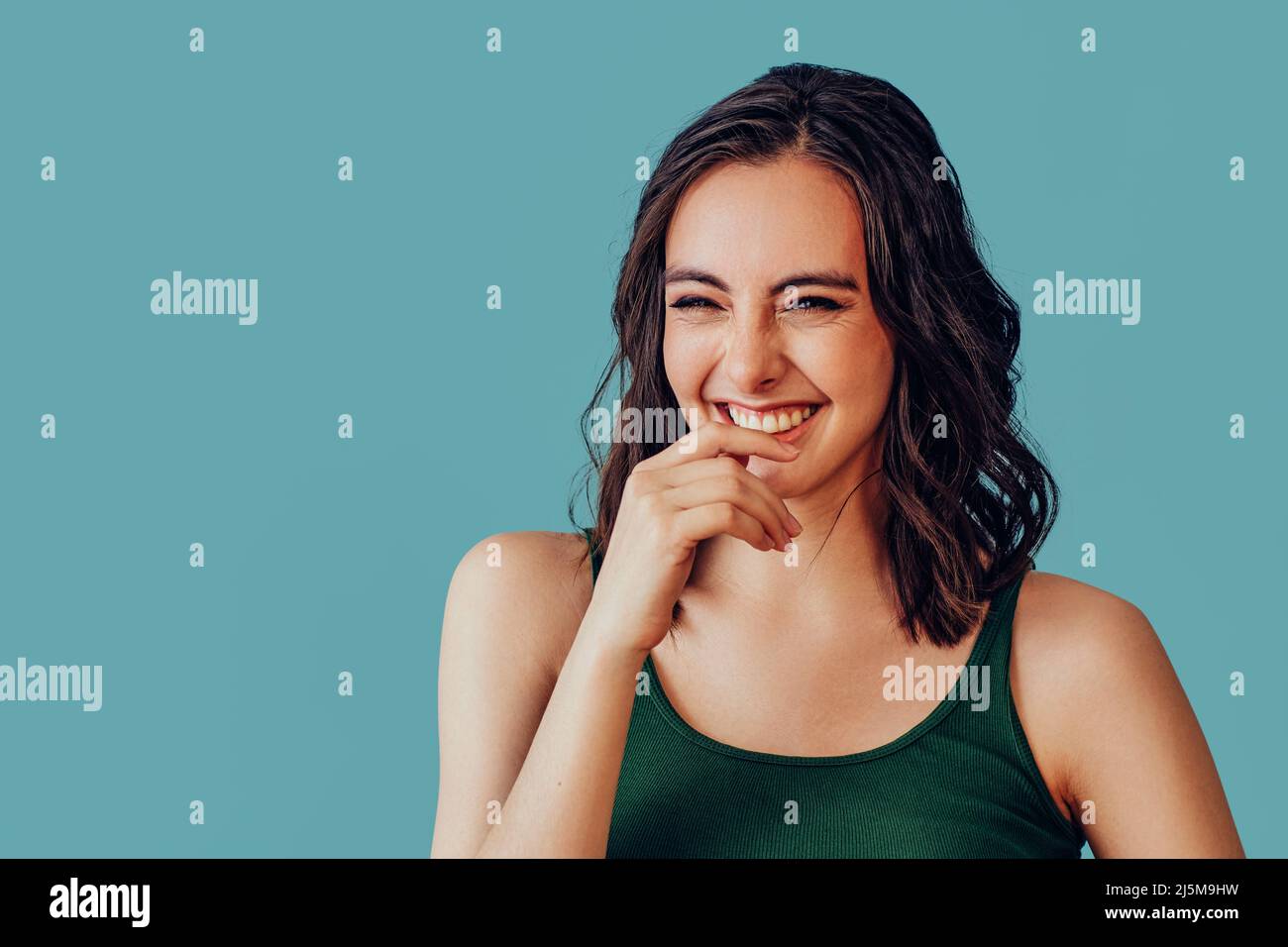 Young adult woman laughing with hand covering mouth studio portrait Stock Photo