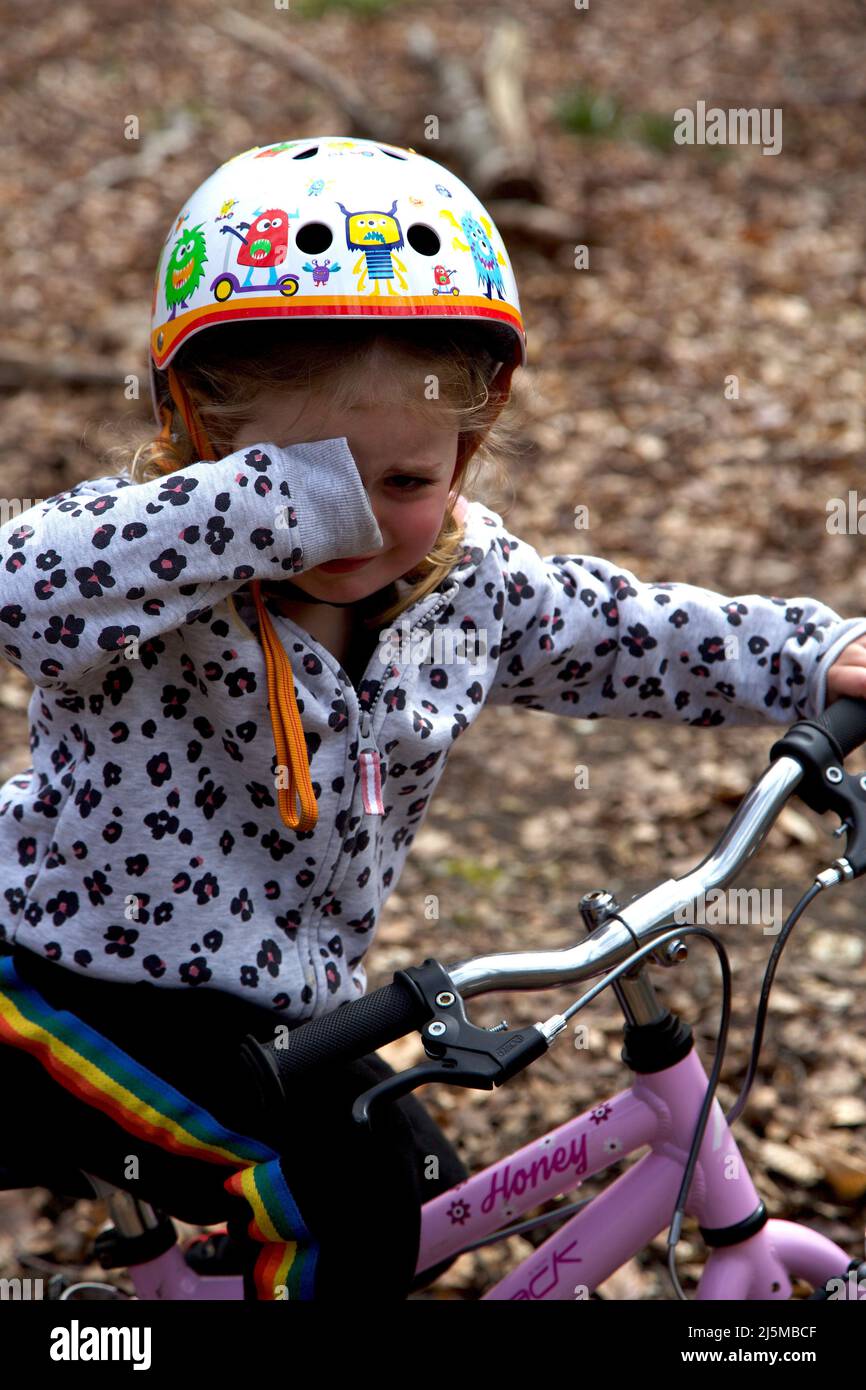 3 year old girl on her bike, crying. UK Stock Photo