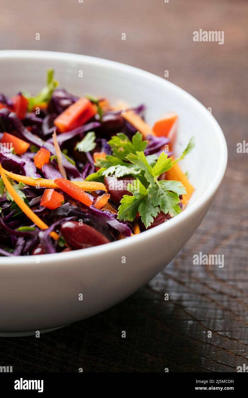 Bowl with a home made Kidney Bean and Purple Cabbage Salad with carrots and red bell pepper. Stock Photo