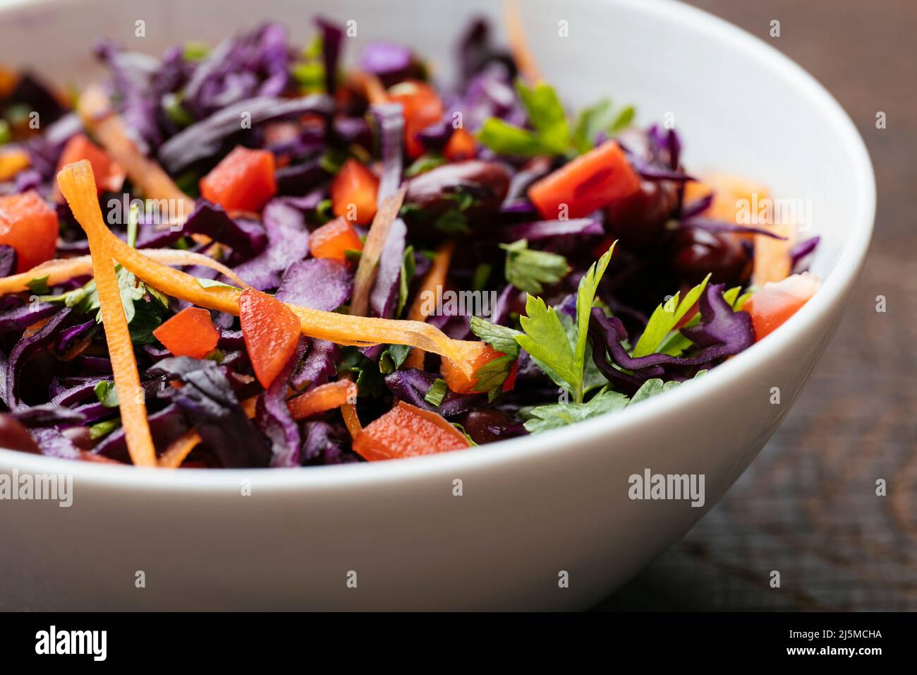 Bowl with a home made Kidney Bean and Purple Cabbage Salad with carrots and red bell pepper. Stock Photo