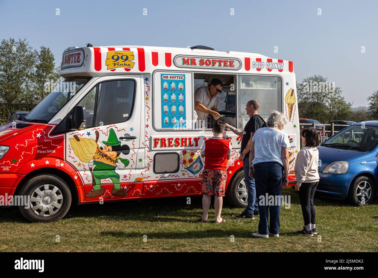 An ice cream vendor serves from his van with eager customers waiting in line Stock Photo