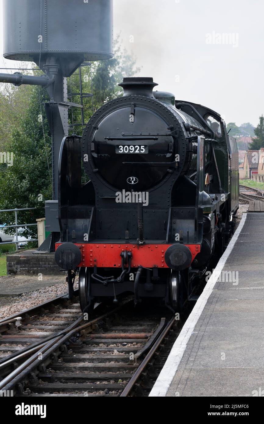 Cheltenham 30925 Schools Class steam locomotive passing a water tower and pulling into Alton train station. Heritage Watercress Line. Hampshire, UK Stock Photo
