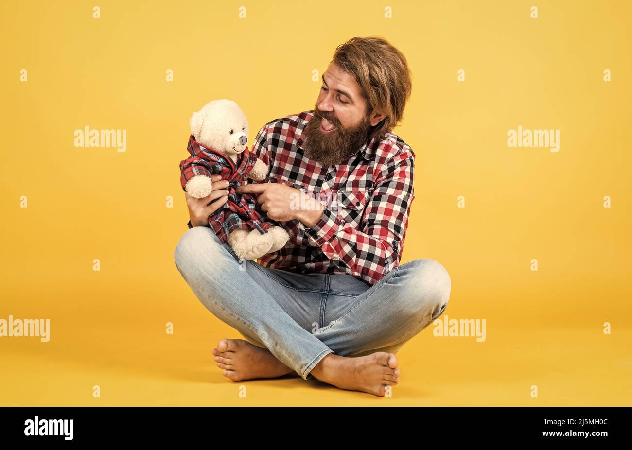 brutal bearded man wear checkered shirt having lush beard and moustache with teddy bear toy, valentines day Stock Photo