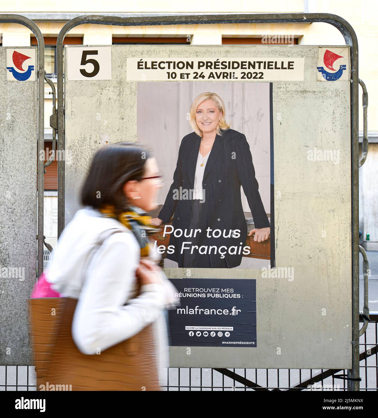 Paris, France. 24th Apr, 2022. A pedestrian passes official campaign posters on an electoral billboard (sign). Presidential posters on their electoral boards. Illustration picture on April 24, 2022 in Paris, France. French voters head to the polls to vote for the second round of the presidential election, to elect their new president of the Republic between Emmanuel Macron (LREM) and Marine Le Pen (RN, 'Rassemblement National'). Credit: Victor Joly/Alamy Live News Stock Photo