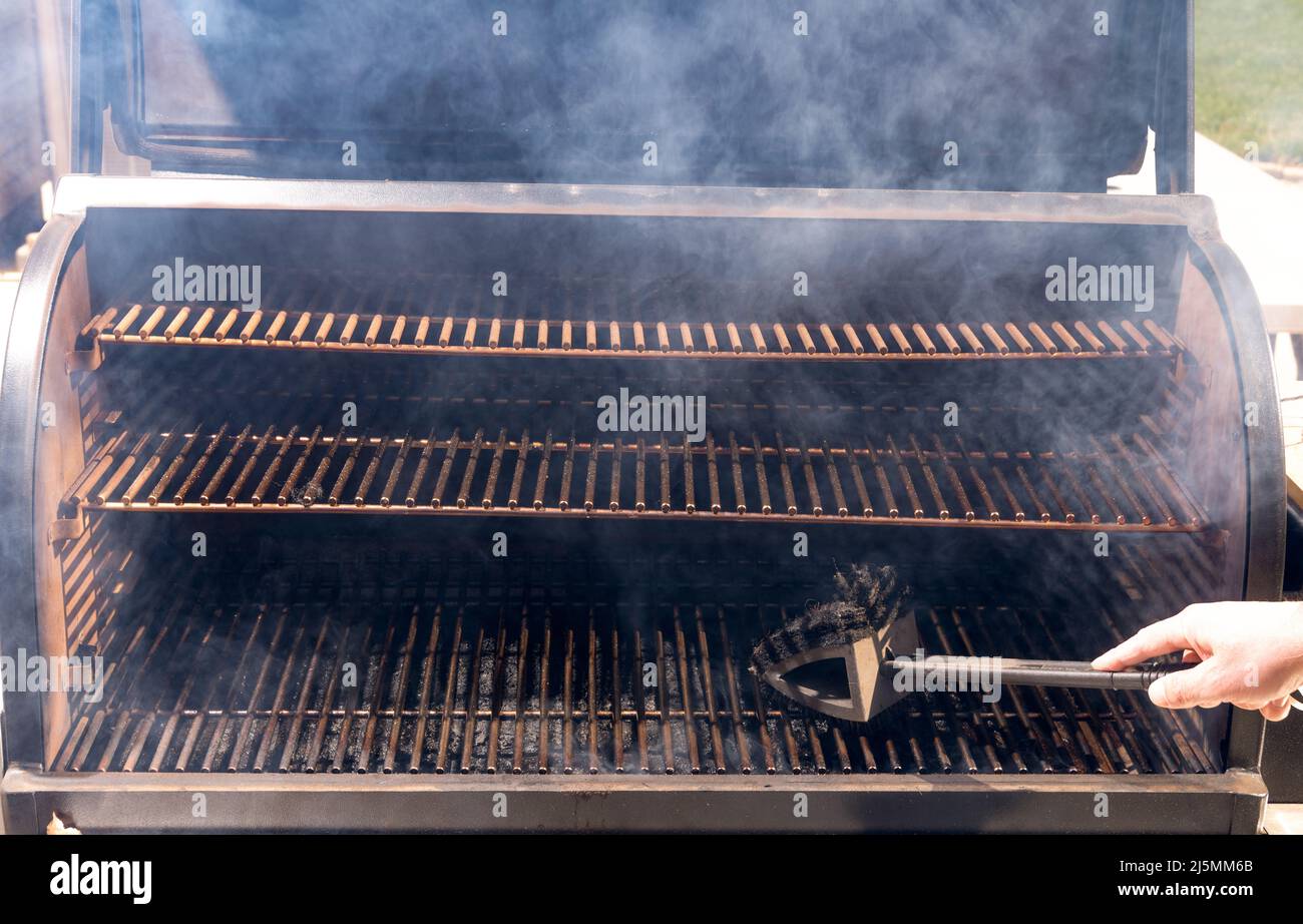 Grill filled with smoke gets a cleaning before the meat is put on Stock