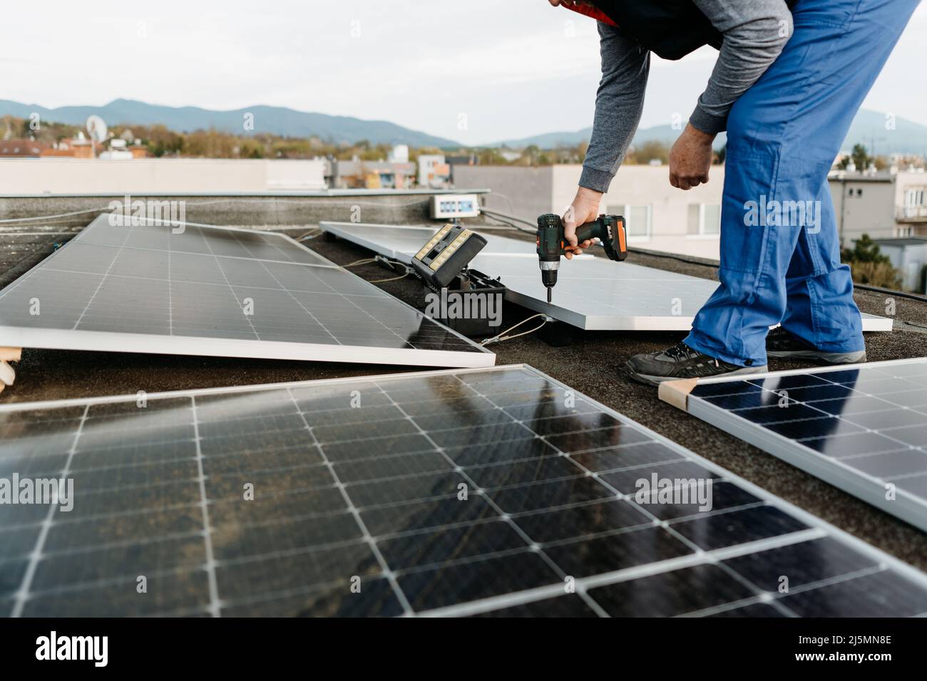 Man worker installing solar photovoltaic panel system using screwdriver. Alternative energy concept Stock Photo
