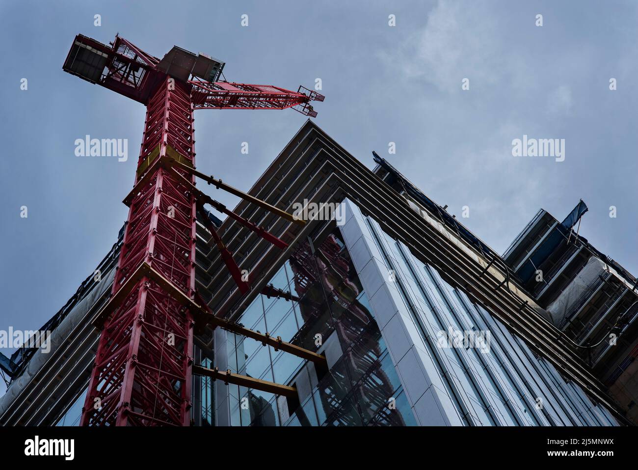 Tower crane attached to the tower block under construction. Building industry. Health and safety. Worksite safety. Stock Photo