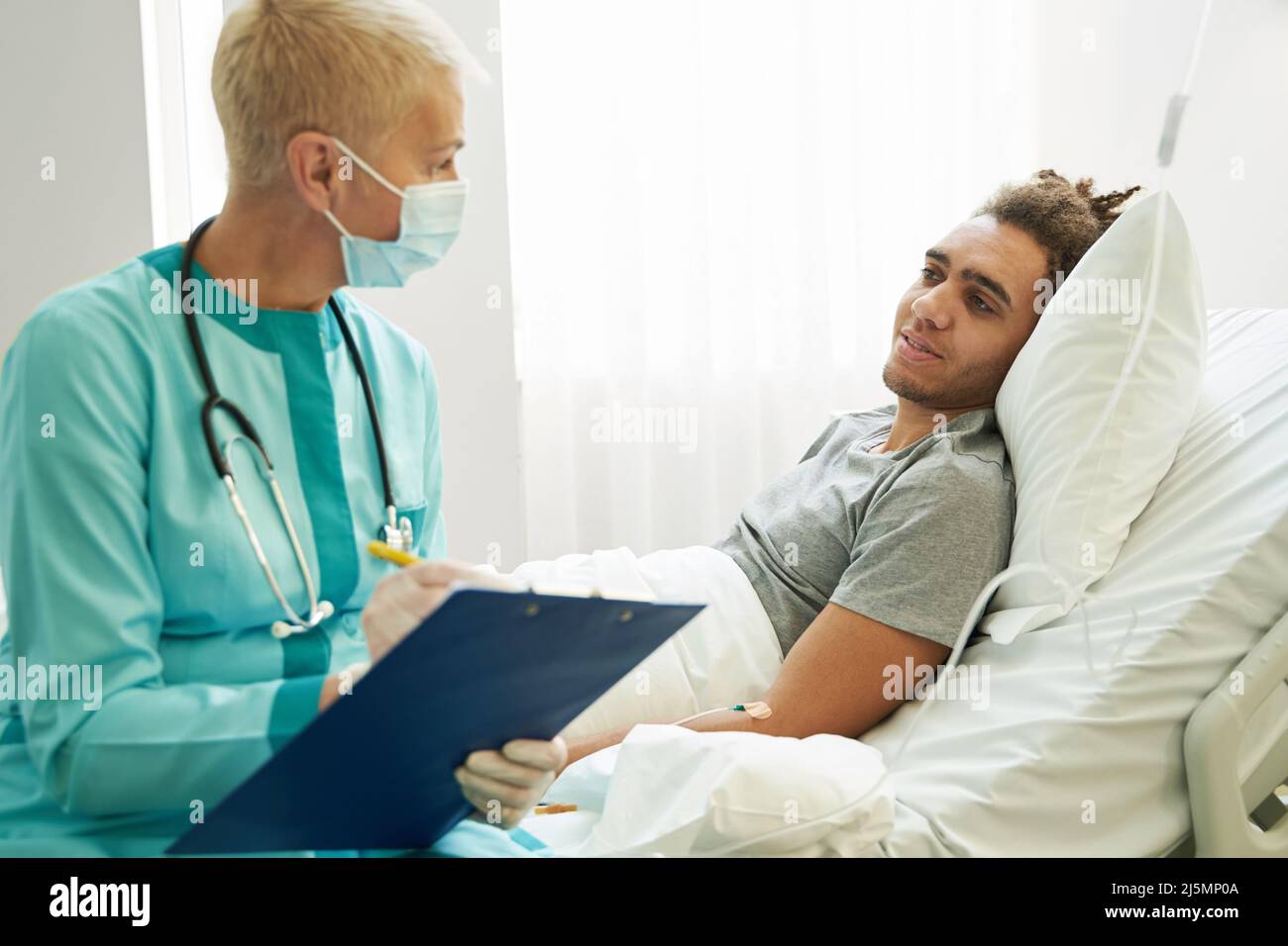 Medical practitioner speaking to patient while taking notes Stock Photo