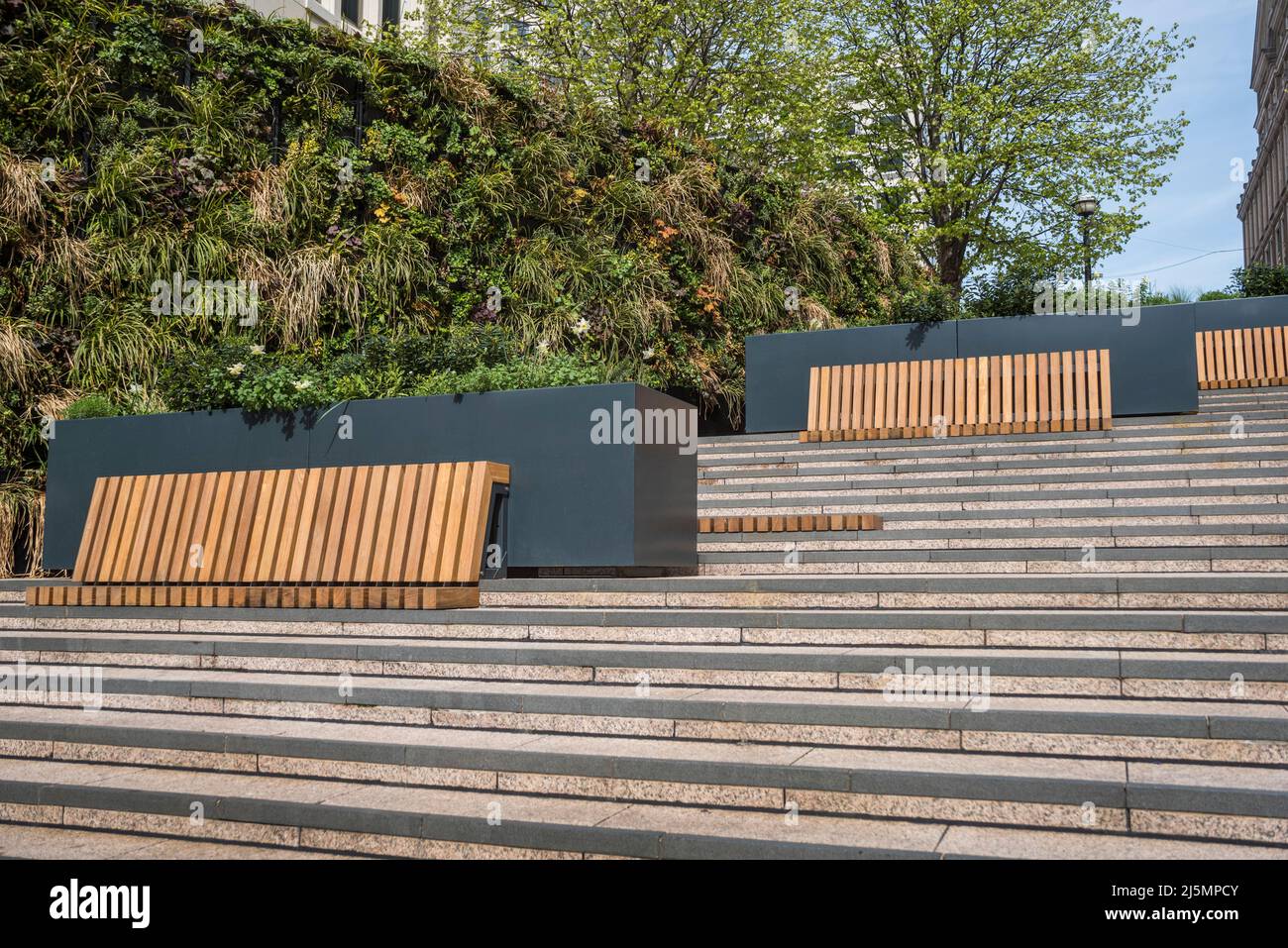 Durable hardwood bench public seating encourage socialising during office lunch breaks. Stock Photo