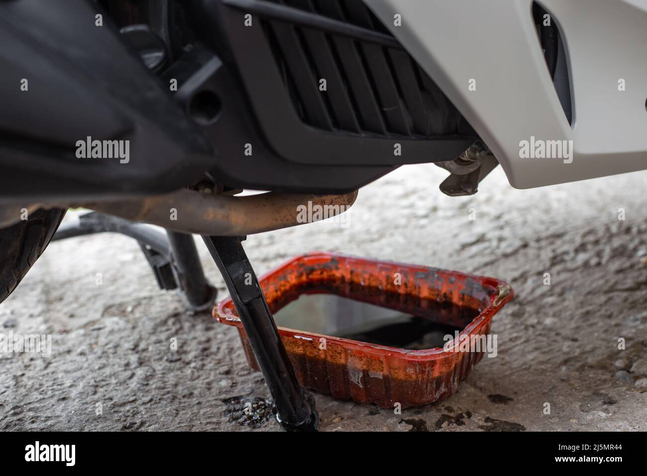 Waste motor oil in a container under the motorbike. Motorcycle