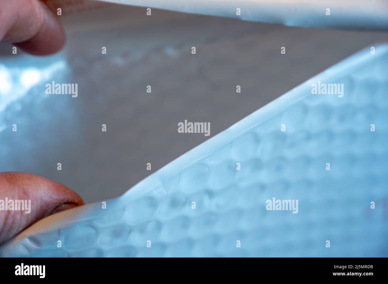 Selective focus on hand opening a padded envelope. Stock Photo