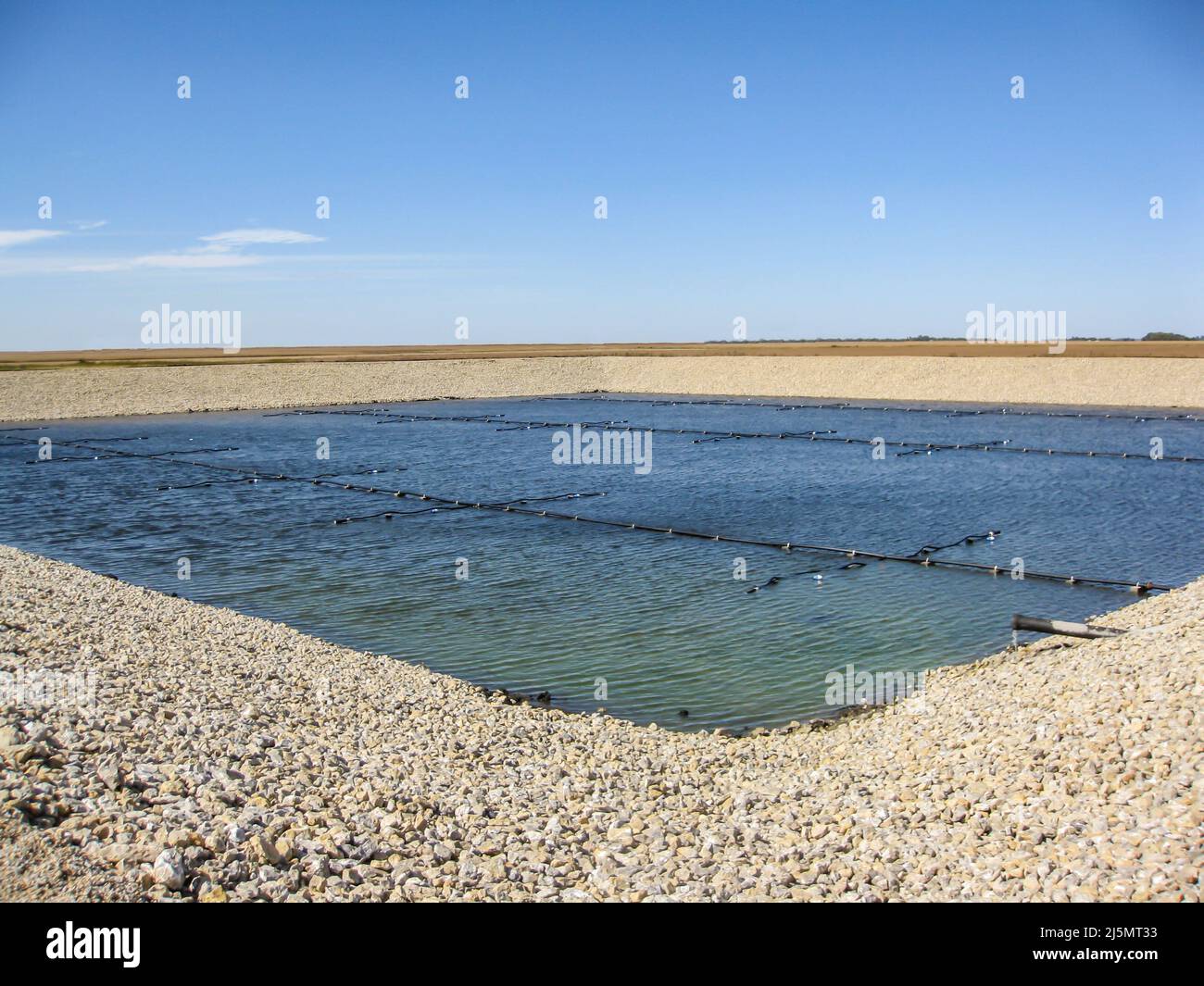 Installation of aeration lines for fine bubbles in an aerobic wastewater treatment lagoon construction project. Stock Photo