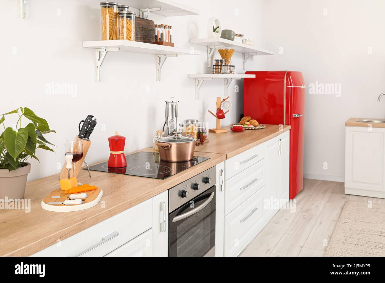 Interior of light kitchen with red fridge, counters and shelves Stock ...