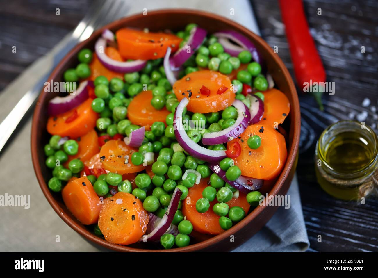 Healthy salad bowl with green peas, carrots and blue onions. Diet food. Fitness salad. Stock Photo