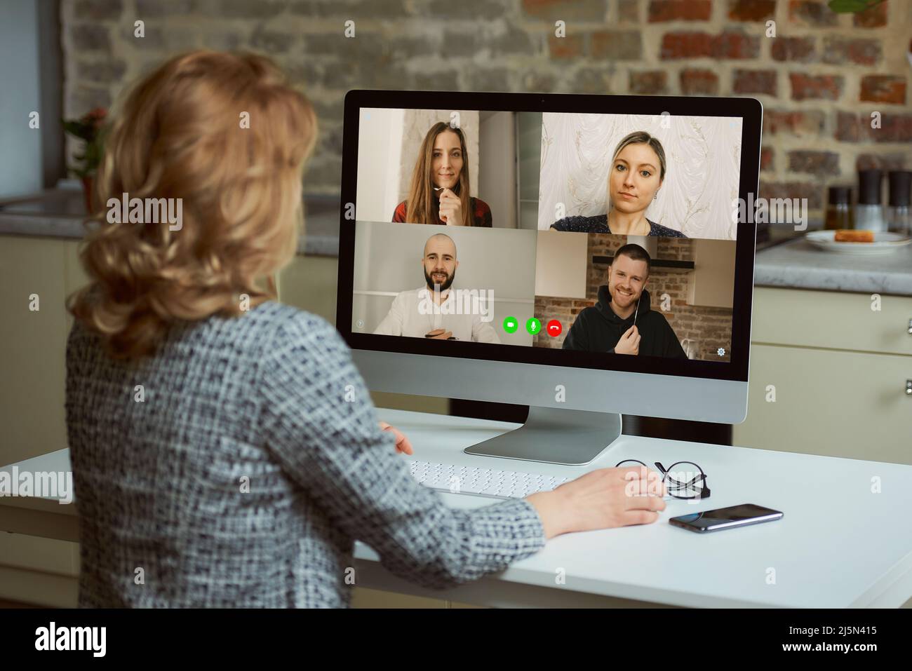 A back view of a woman who listens to reports of employees on an online briefing Stock Photo