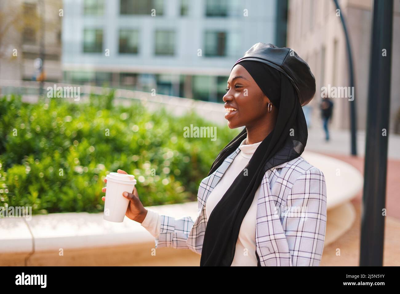 Happy Muslim black woman drinking coffee and laughing Stock Photo