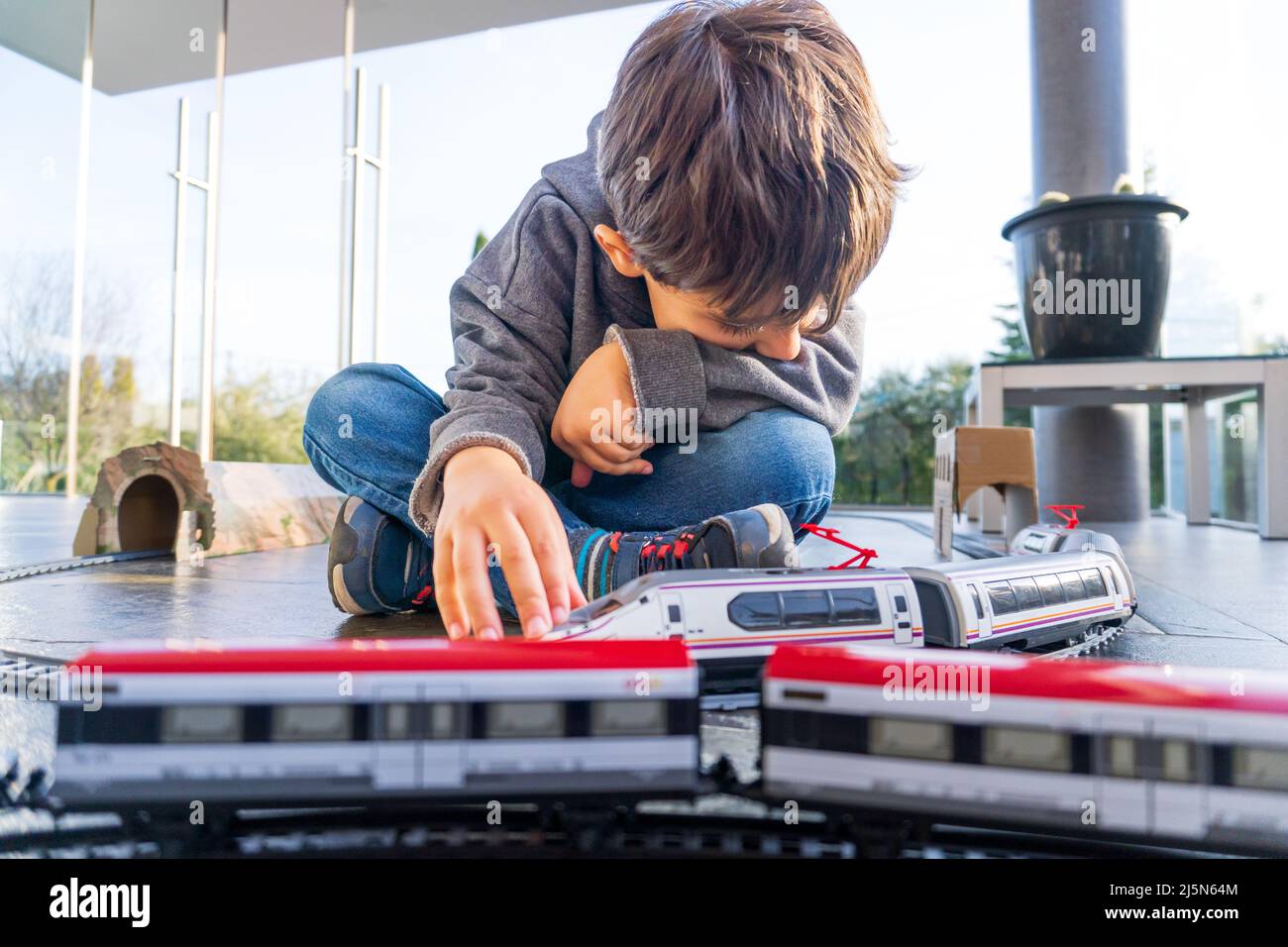 vYoung kid playing with toy trains on the floor. Toy train similar to
