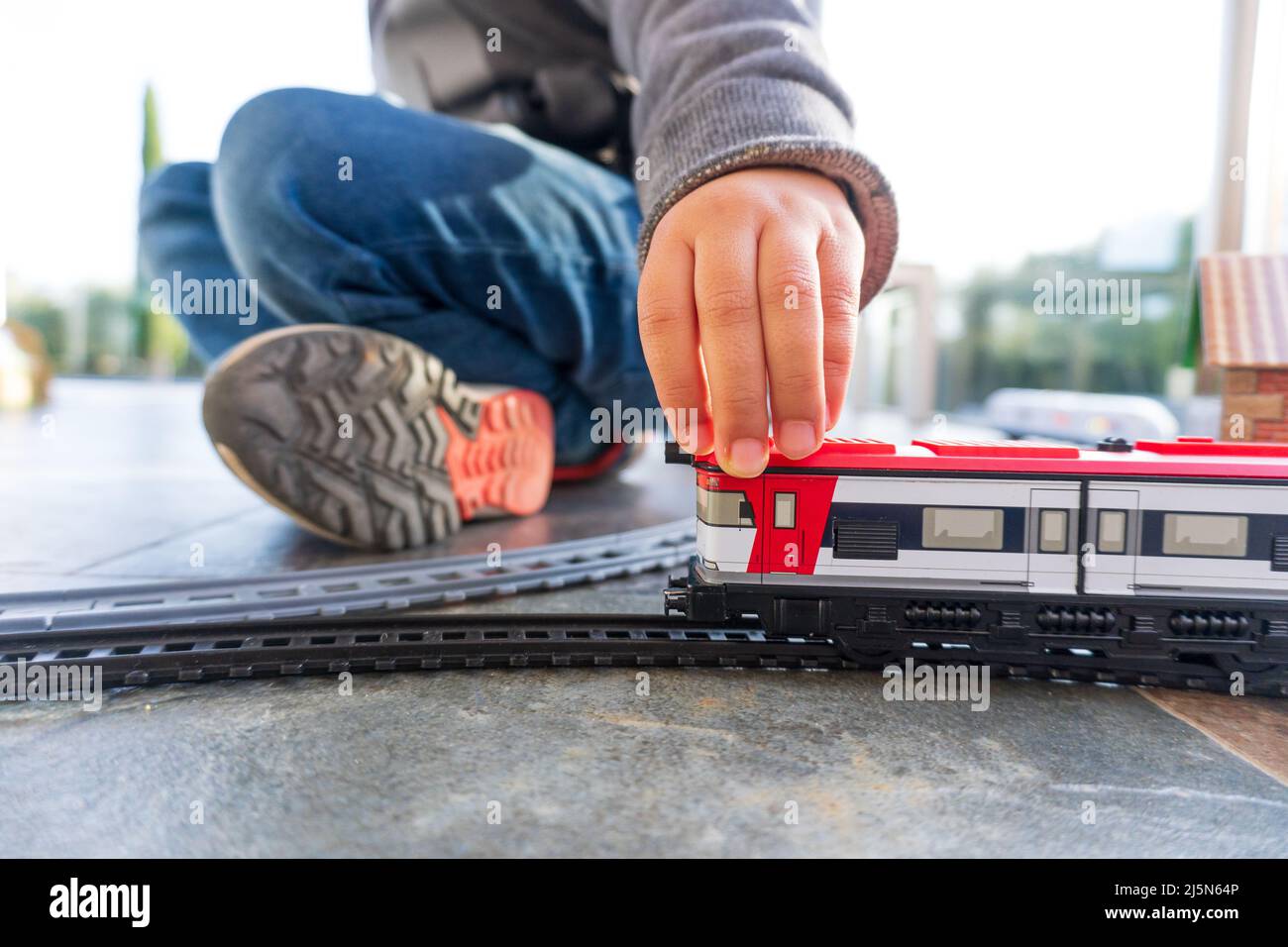 vYoung kid playing with toy trains on the floor. Toy train similar to