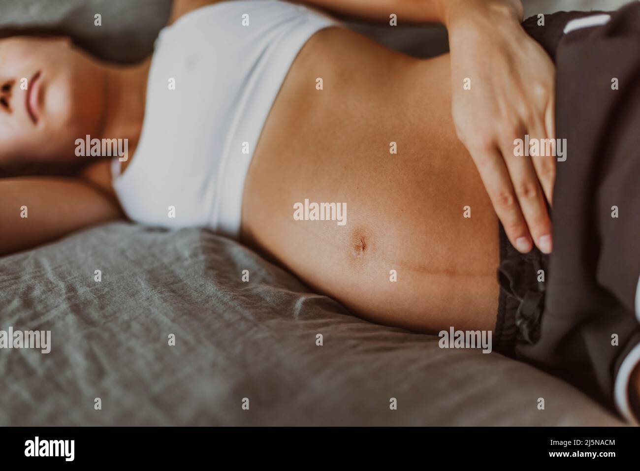 Pregnant woman lying in bed sad of depression or having or sleep problem. Closeup of belly skin with dark line from pregnancy symptom Stock Photo