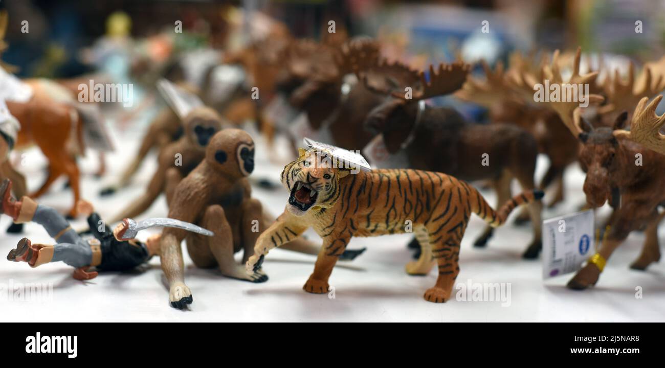 Animal figurine toys including a tiger, monkeys and moose and one fallen human figure for sale in a gift shop. Stock Photo