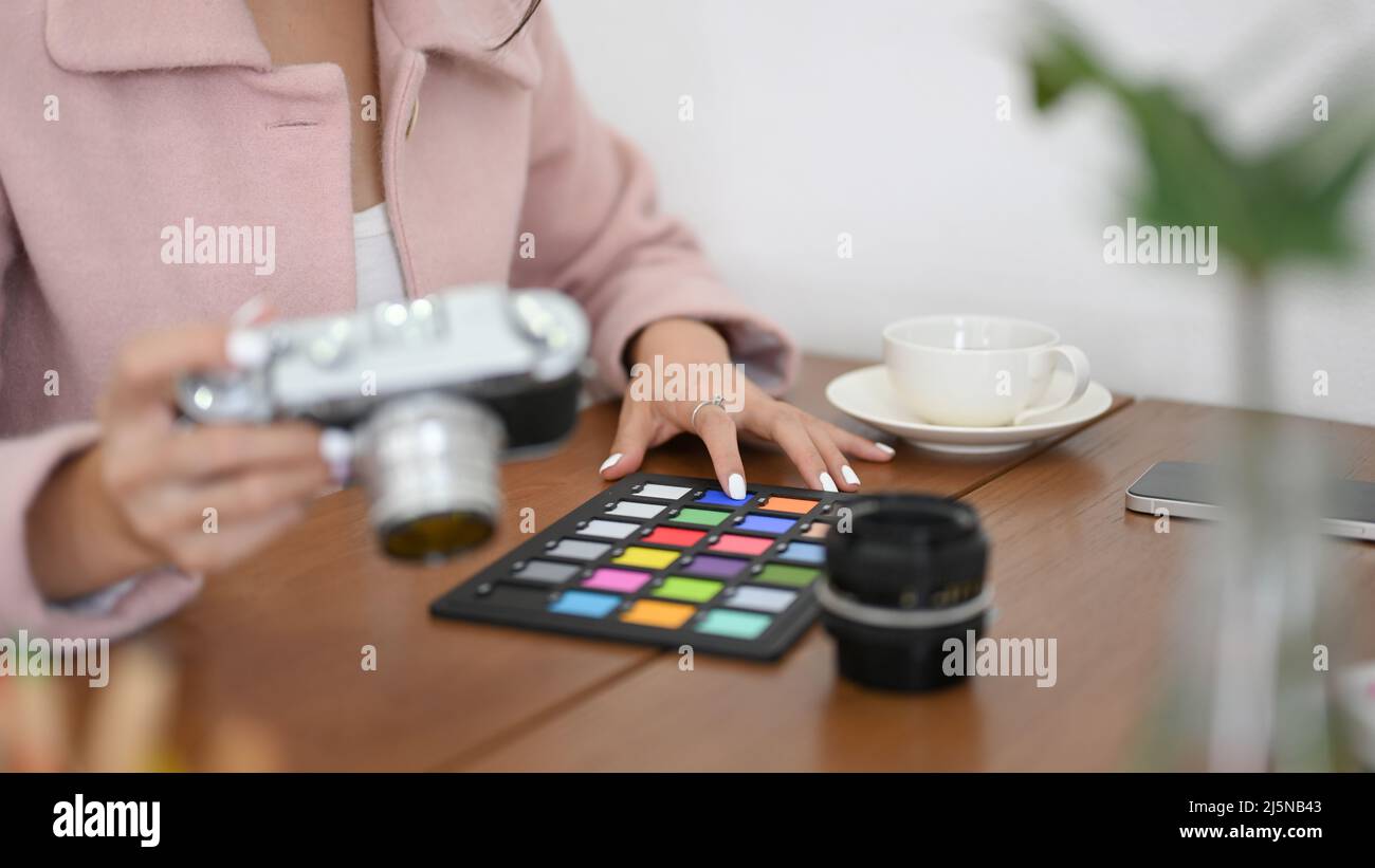 Cropped image, Professional millennial female freelance photographer or blogger checking her camera and colour-checker. Stock Photo