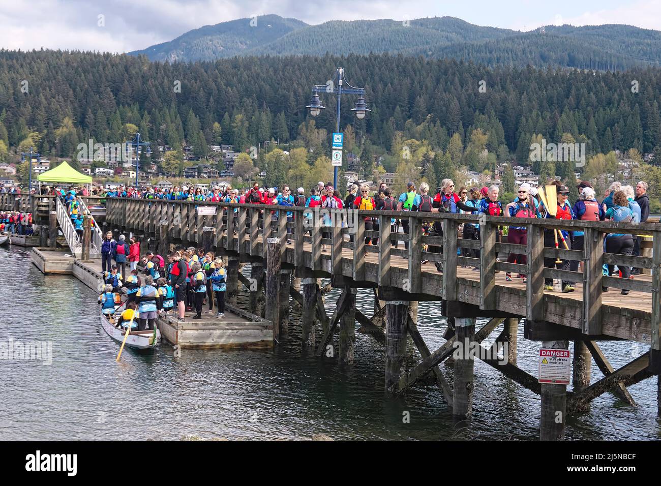 Dragon boat competitors and spectators walking along the pier at Rocky Point Park, Port Moody, B. C., Canada during the Inlet Spring Regatta 2022. Stock Photo