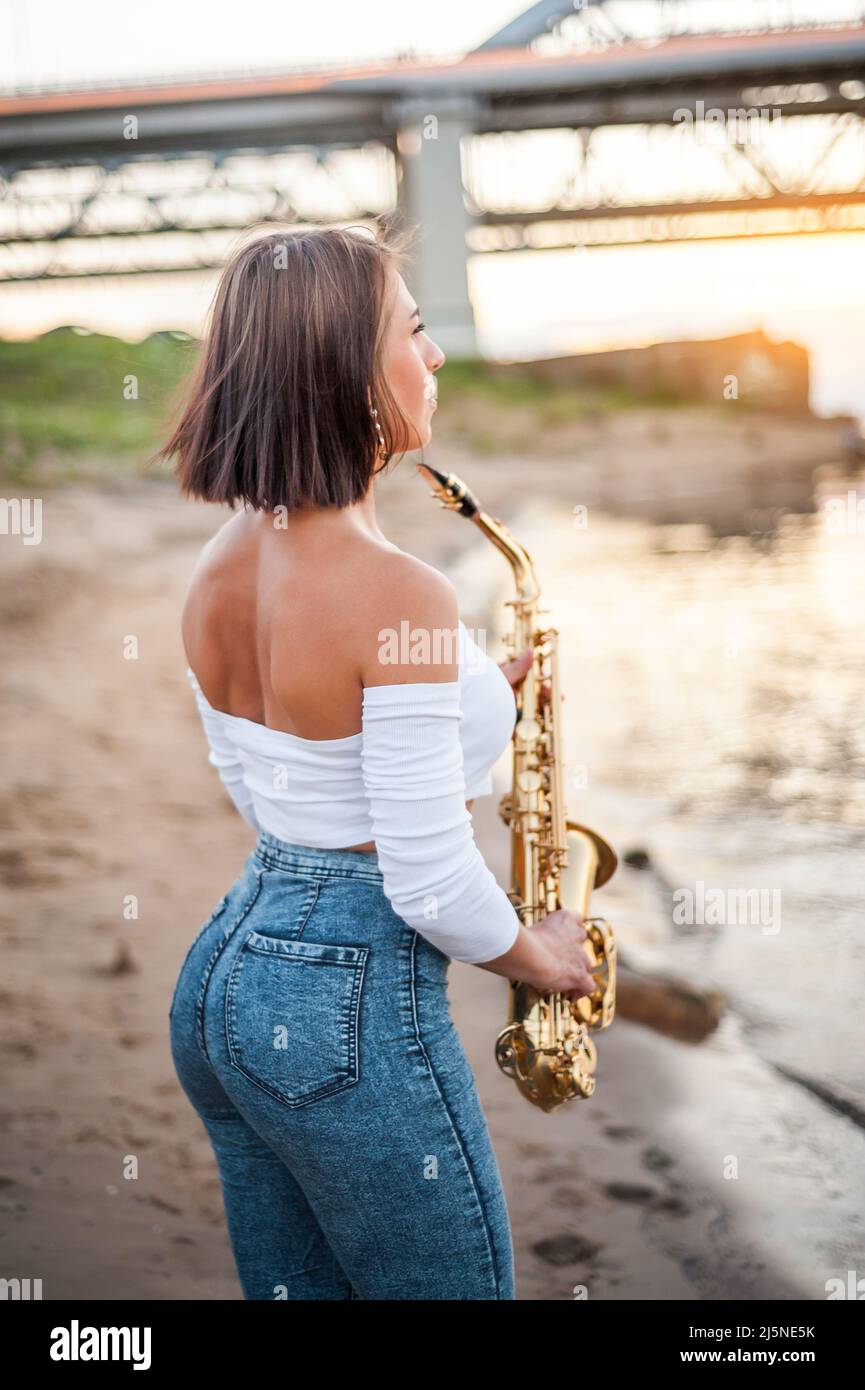 Woman playing the saxophone at sunset Stock Photo