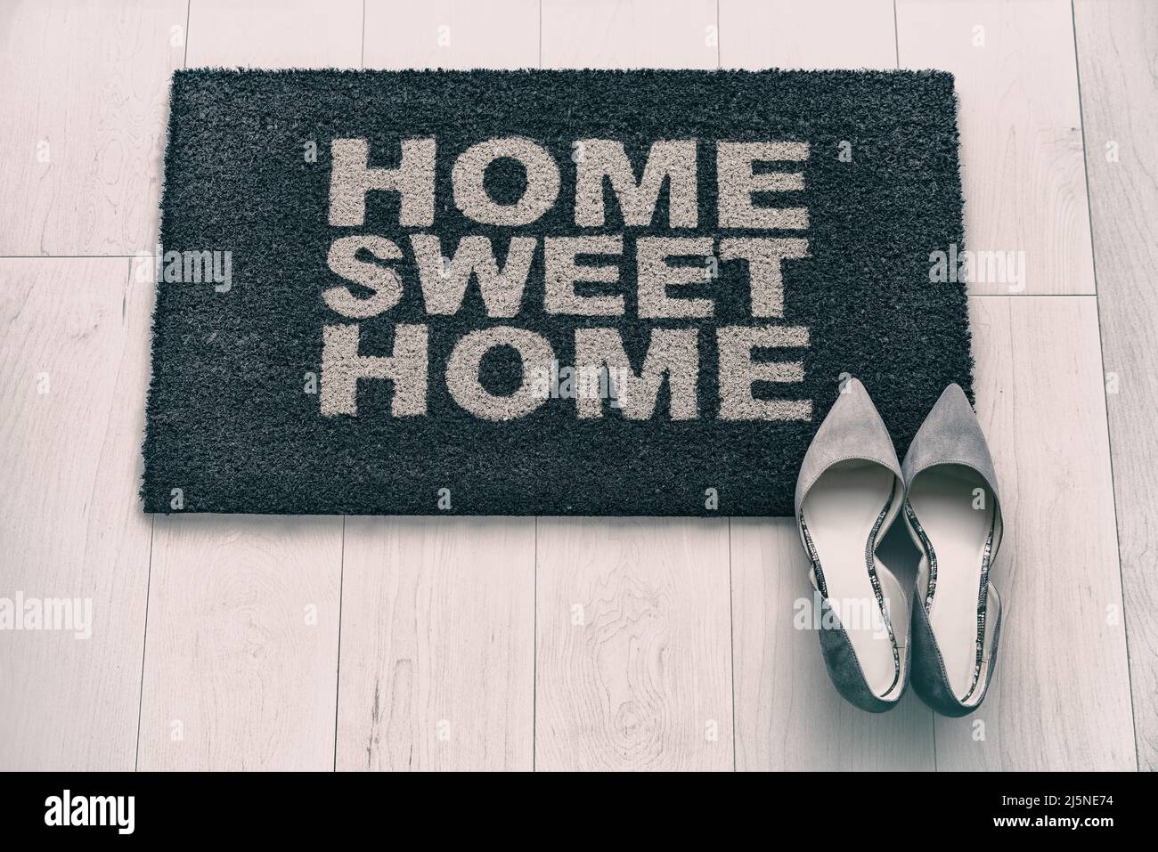 New condo front door mat top view. Modern living business woman high heel shoes on Home Sweet Home entrance doormat. Homeowner moving in concept Stock Photo