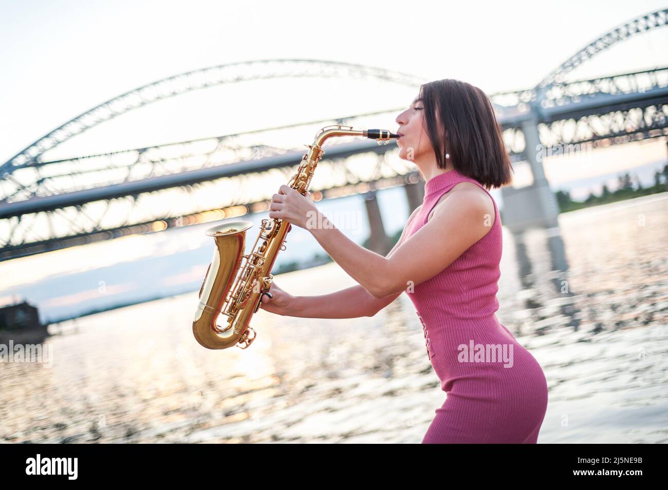 Woman playing the saxophone at sunset Stock Photo